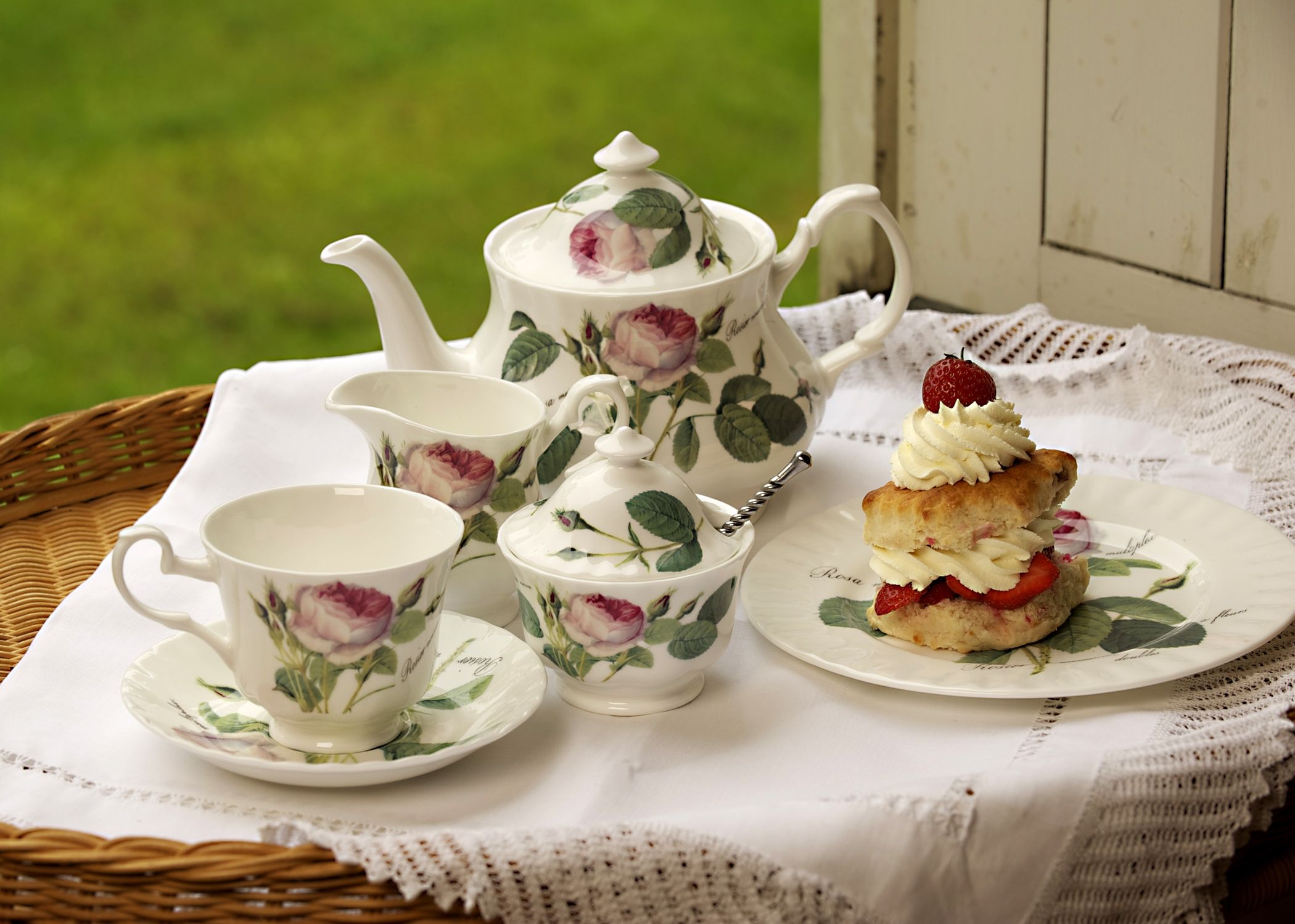 Teapot, milk jug, sugar bowl and cup and saucer together with cream scone ready for afternoon tea